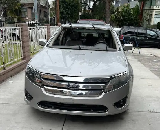 Silver Ford Fusion with its windshield removed before replacement