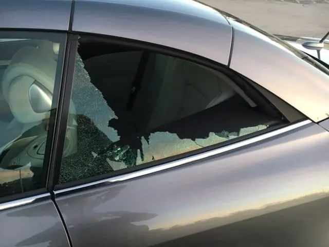 Shattered rear quarter window on a gray coupe